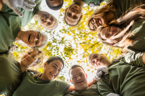 Group of volunteers including people with down syndrome embracing after a successful forest cleanup