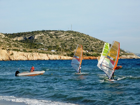 August 10, 2022. Windsurfers at sea, in the bay of Varkiza, in Athens, Greece