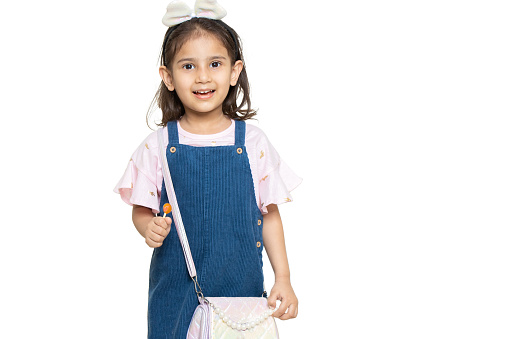 Little indian girl child wearing casual cloth and hand bag standing isolated over white background. Kids fashion portrait, Copy space.