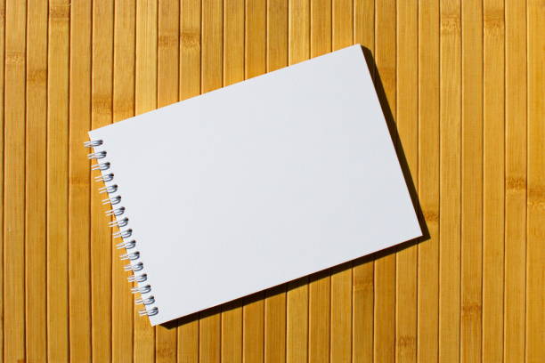 istock Open sketchbook with blank white page and spiral on a bamboo background 1533515033