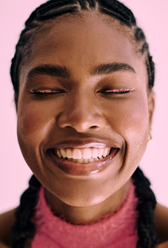 beautiful black woman smiling wearing pink makeup and cornrows. Stock photo