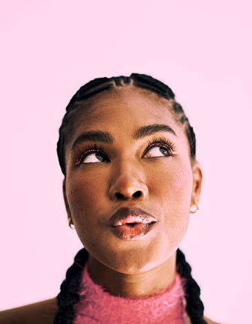 Headshot of a beautiful black young woman standing while looking up and pouting. Stock photo
