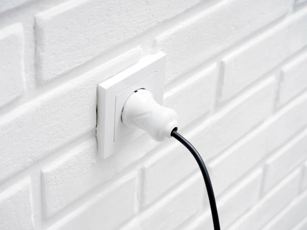 istock Electric plug and socket on white brick wall background, power energy concept 1533575967