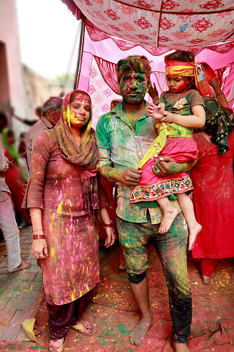 Family celebrating Holi festival during day time. Holi is a popular and significant Hindu festival celebrated as the Festival of Colours, Love and Spring. It celebrates the eternal and divine love of the god Radha and Krishna.