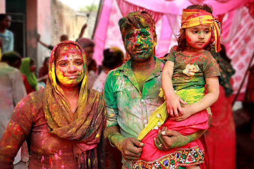 Family celebrating Holi festival during day time. Holi is a popular and significant Hindu festival celebrated as the Festival of Colours, Love and Spring. It celebrates the eternal and divine love of the god Radha and Krishna.