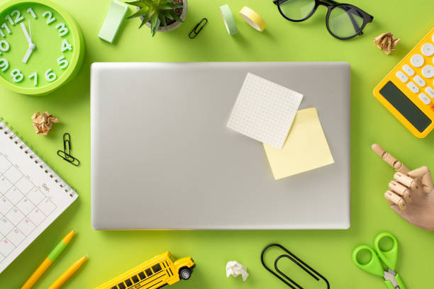 istock Step into the world of online studying from home with this captivating top-down view, presenting a laptop and various stationery on a light green background. Room for text or advertisements 1533613786