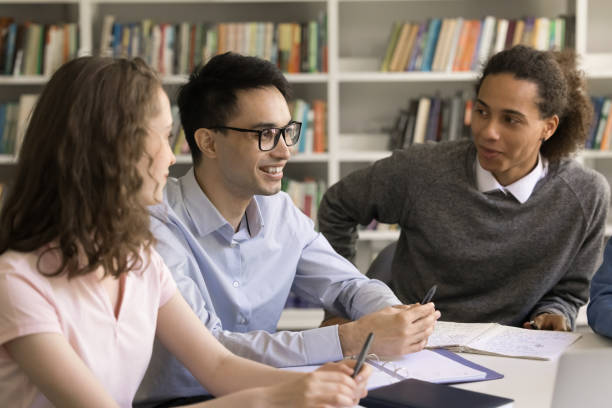 istock Positive diverse young college students discussing school essay in library 1533629083