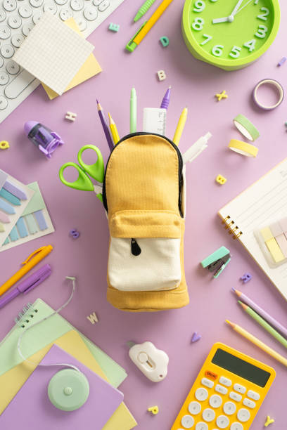 istock Explore the possibilities of remote learning with this top-down vertical snapshot displaying a keyboard, clock, planner, pen, pencil case with wide range of office supplies on pastel purple background 1533660395