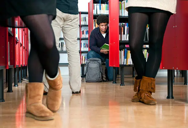 Kneeling man, reading a book in a public library