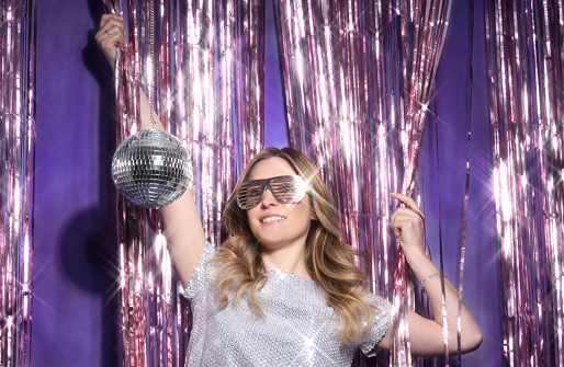 Beautiful stylish woman posing on shiny background with disco ball
