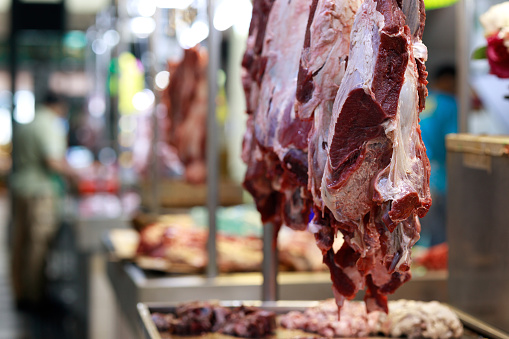 Pieces of raw red meat hanged in the Asian butcher's store