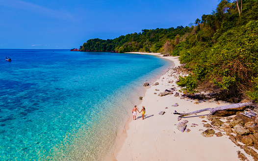 drone view at the beach of Koh Kradan island in Thailand, aerial view over Koh Kradan Island Trang, couple of men and women on the beach during vacation in Thailand