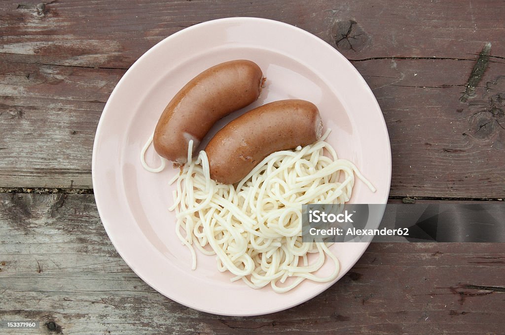 Macaroni and small sausages Macaroni and small sausages in a pink plate on a wooden table Brown Stock Photo