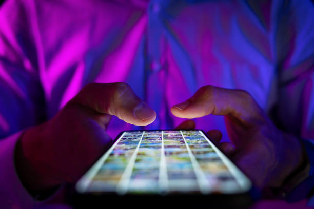 istock man scrolling mobile phone screen in dark room with neon lights. internet browsing, social media and marketing 1533728507