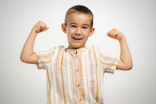 Portrait of a happy child boy showing off her muscles