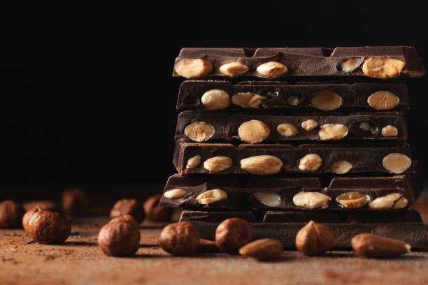 istock Dark and milk chocolate with nuts on a dark background sprinkled with cocoa powder. 1533740466