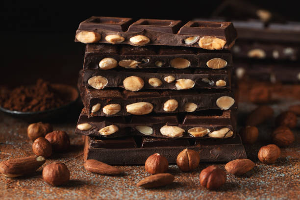 istock Dark and milk chocolate with nuts on a dark background sprinkled with cocoa powder. 1533740472