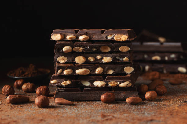 istock Dark and milk chocolate with nuts on a dark background sprinkled with cocoa powder. 1533740473