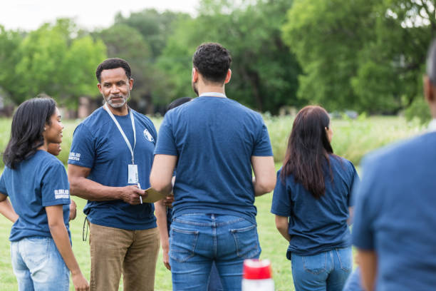 istock Mature male volunteer coordinator talks to student group 1533752120