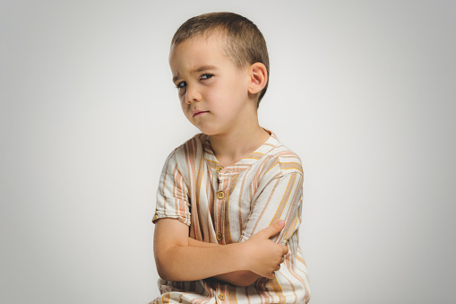 Studio shot portrait of a child boy with broken heart, on grey background