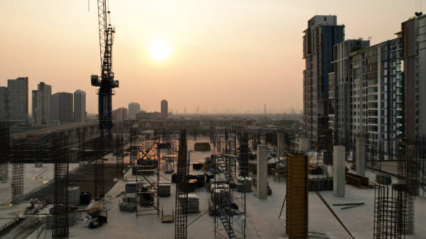 Power crane and new construction high building, New construction site with cranes on orange sunset, sunrise sky background. Steel frame structures and structural steel beams build large buildings at the construction site. construction machinery.