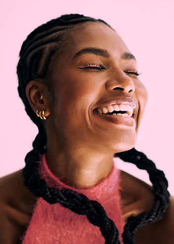 beautiful black woman shot against a pink background  with cornrow pigtails laughing . Stock photo
