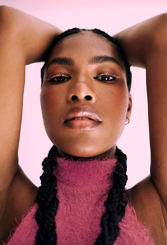 an up close shot of a beautiful black woman with pink fashion make up and standing in front of a pink background. Stock photo