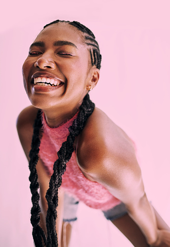 Shot of a beautiful and vibrant young black woman smiling into camera in front of a pink background Stock photo