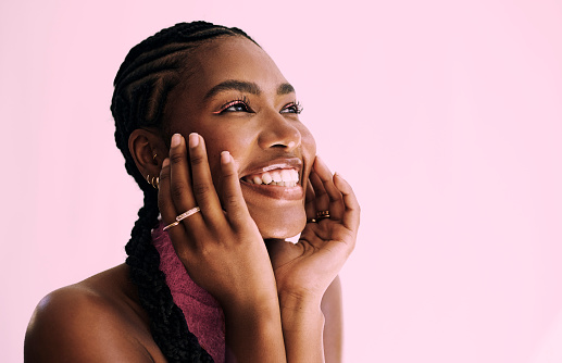 a close up shot of a beautiful young black woman smiling in front of a pink backdrop. Stock photo, copy space