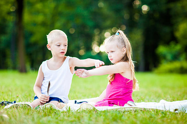 Happy family - little boy and girl having fun in green scenerie, curious with ladybird