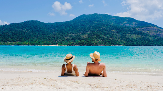 Couple on the beach of Koh Lipe Island Thailand, a tropical Island with a blue ocean and white soft sand. Ko Lipe Island Thailand. men and women relaxing on the beach looking out over ocean