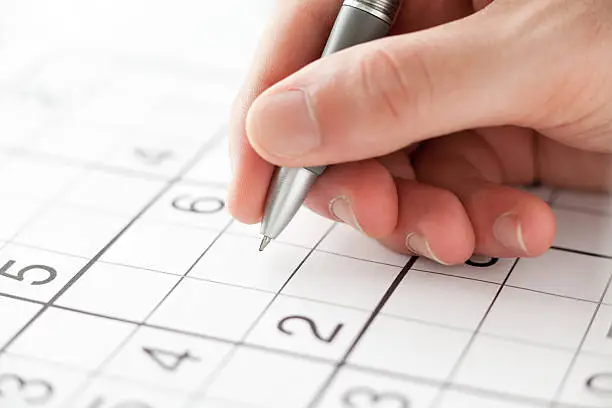 Hand Holding a Pen Playing Sudoku