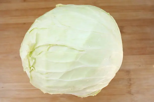 green cabbage on wooden chopping board
