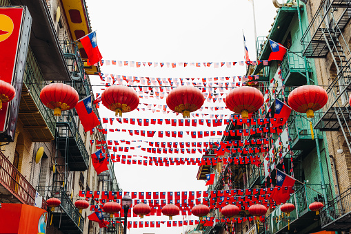 Low-angle view of colourful streets of old district of China Town decorated by Chinese lights and the flags of Taiwan and the United States