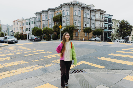 Front View of smiling female in colourful sweater walking in the old downtown streets of San Francisco in the United States