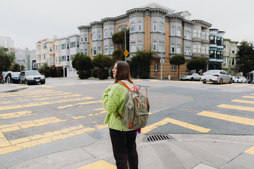 Rear View of smiling female in colourful sweater walking in the old downtown streets of San Francisco in the United States