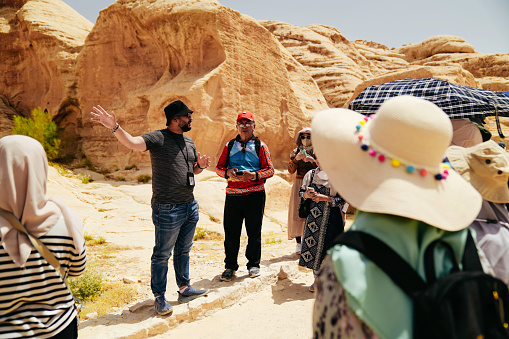 Tour guide explaining petra city to tour group  Asian Traveler admiring the treasury of Petra, named El Khasneh al Faroun