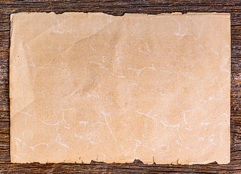 Sheet of old paper on a wooden background. Old paper on brown aged wood.