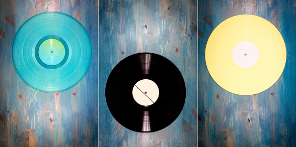 Collection of images with different color vinyl records on blue wooden background