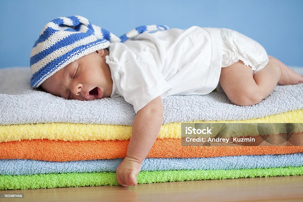 Yawning sleeping baby on colorful towels stack Babies Only Stock Photo