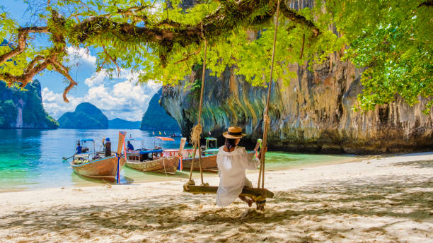 women on a swing at the Tropical lagoon of Koh Loa Lading Krabi Thailand part of Koh Hong Islands women on a swing at the Tropical lagoon of Koh Loa Lading Krabi Thailand part of the Koh Hong Islands in Thailand. beautiful beach with limestone cliffs and longtail boats krabi province stock pictures, royalty-free photos & images