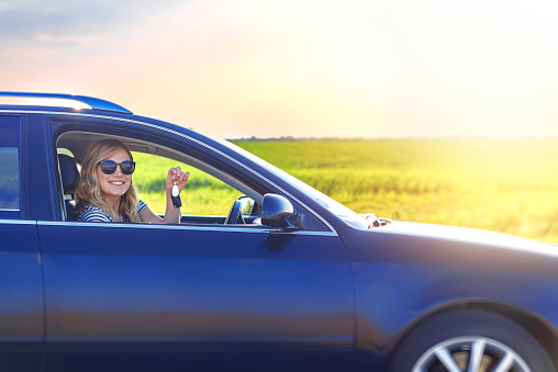 A beautiful blonde woman holds a car key in her hand. Woman car driver.