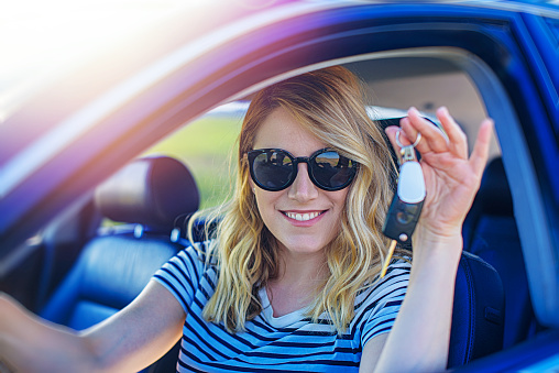 A beautiful blonde woman holds a car key in her hand. Woman car driver.