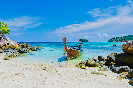 couple on the beach of Kla Island in front of Koh Lipe Island Southern Thailand, with turqouse colored ocean and white sandy beach with a kayak