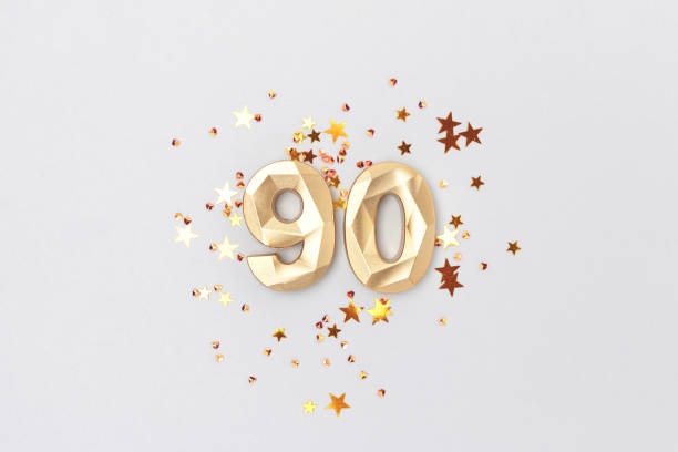 istock Gold colored number 90 and stars confetti on a blue background. 1533924236