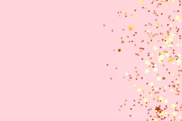 istock Glowing gold colored stars and crystals confetti on a pink background. 1533925086