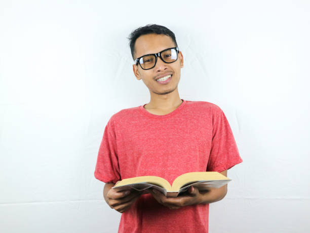 istock Handsome Asian man smiling and holding and reading book in hand 1533949805