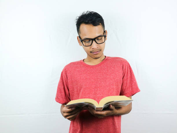 istock portrait of asian man holding book with reading focused expression. 1533949813