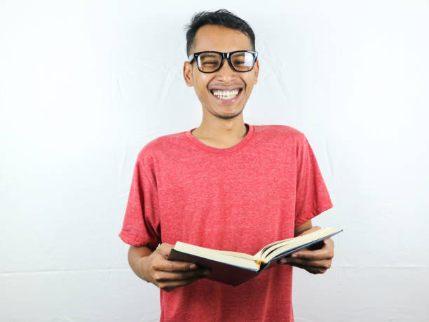 istock Handsome Asian man smiling and holding and reading book in hand 1533954274