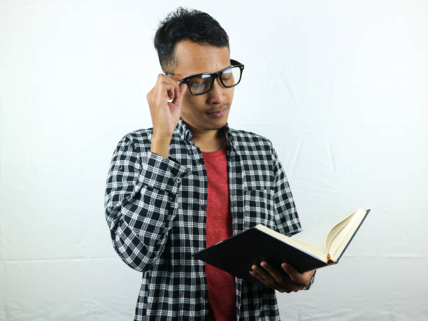 istock Handsome Asian student smiling and holding and reading book in hand 1533956509